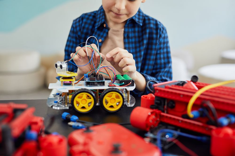 A young student wiring a robot car